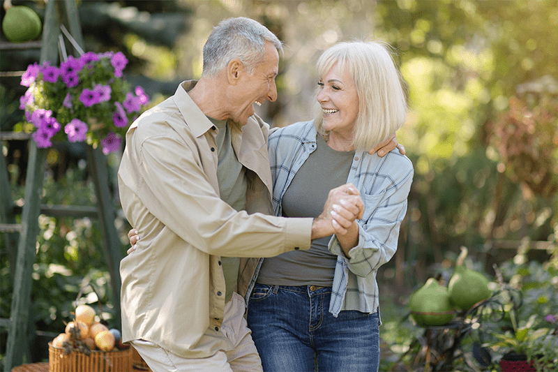 Happy senior couple holding hands in garden celebrating an occasion